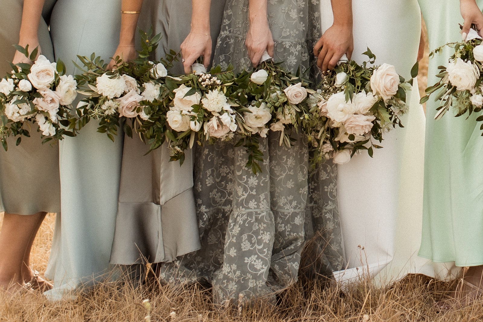 Bride and wedding party holding sage green toned and white wedding flower bouquets