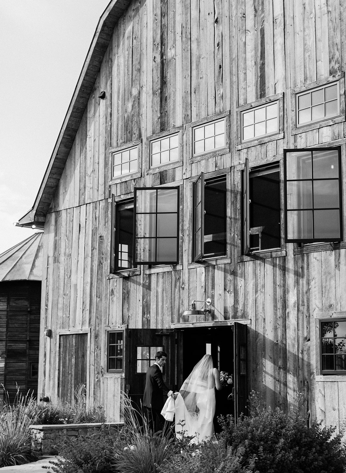 Bride and groom walk into a rustic barn at their Bozeman wedding in Montana