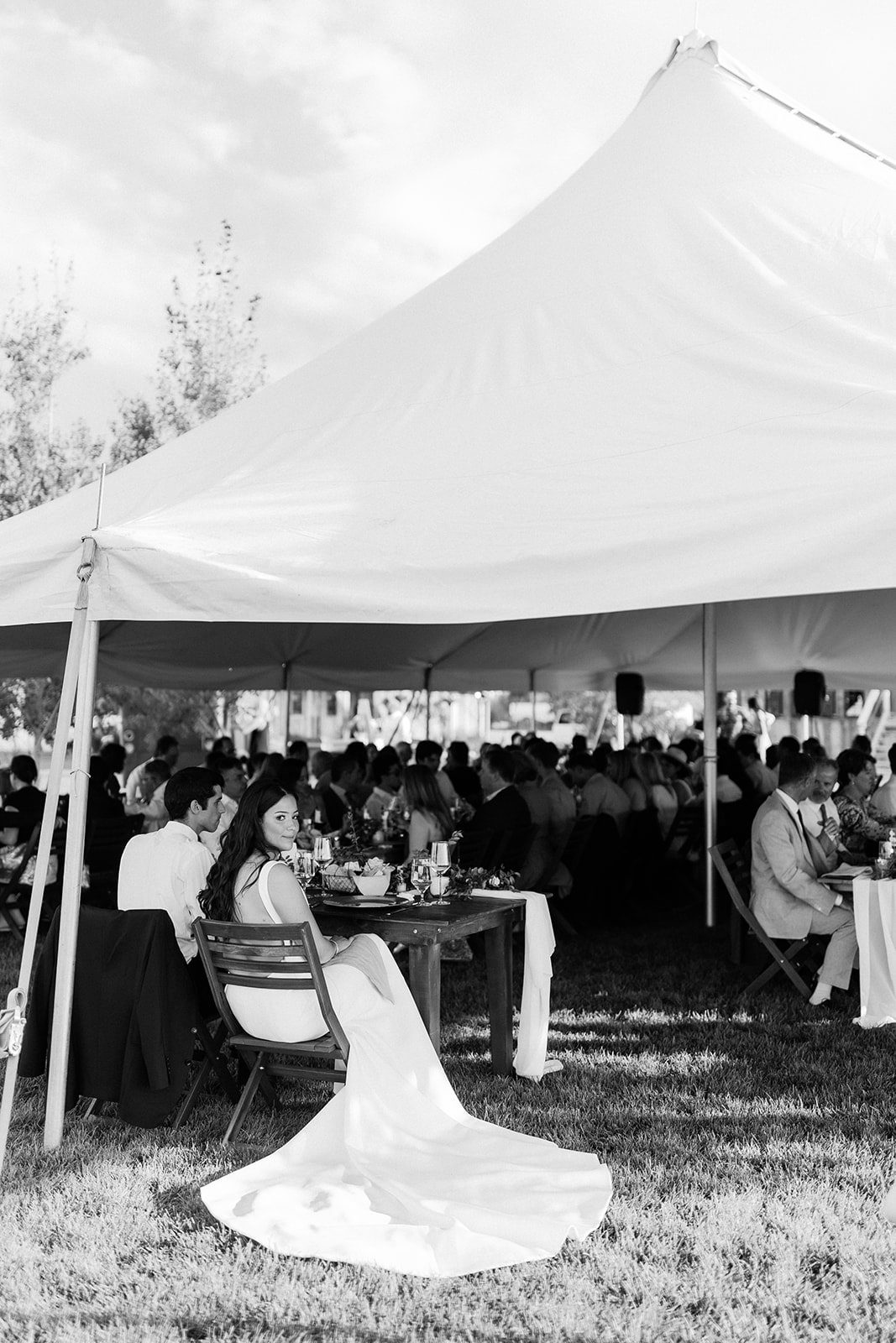 Bride and groom eat with guests under a tent during their Bozeman wedding reception