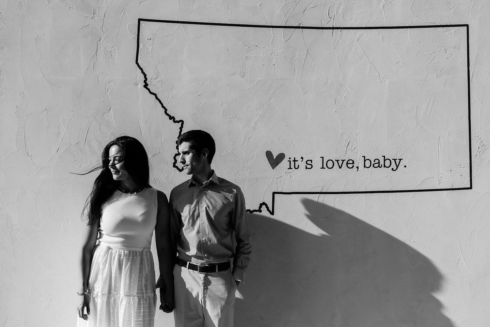 Bride and groom hold hands in front of a Montana mural in downtown Bozeman