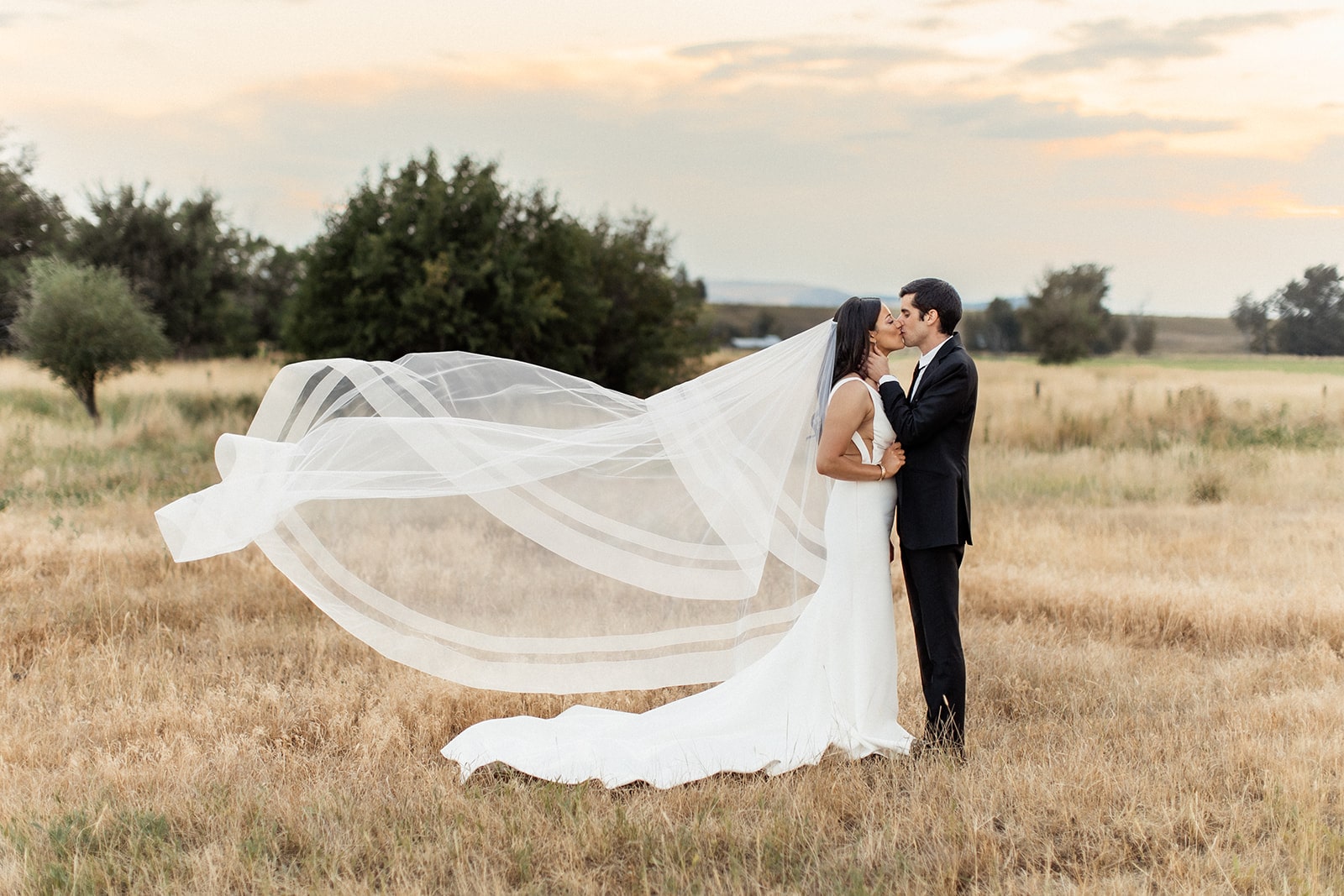 Bride and groom kiss in the field during their Bozeman wedding at Firelight Farm