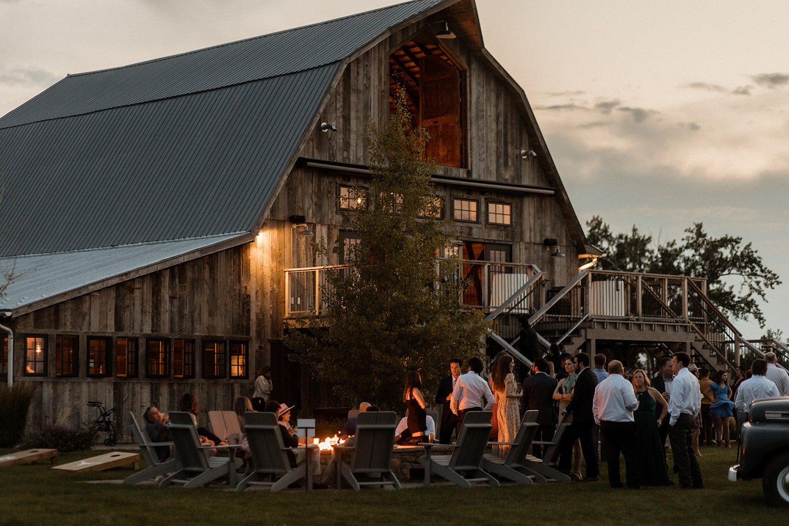 Guests mingle around a campfire during sunset at Firelight Farm wedding