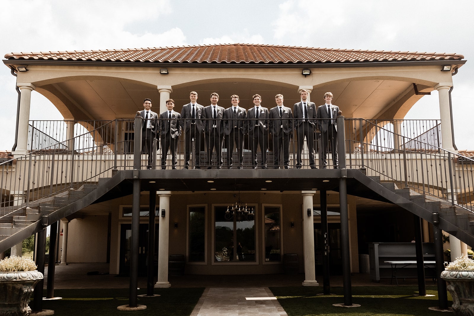 Groom and groomsmen stand at the top of a black iron staircase at D'vine Grace Vineyard