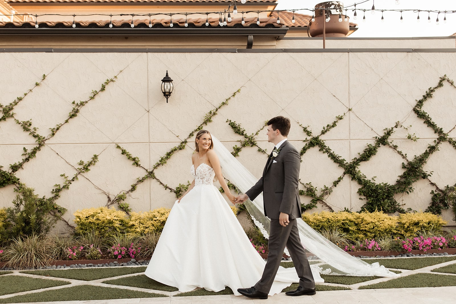 Bride and groom hold hands while walking around the grounds at their Italy-themed north Texas wedding venue