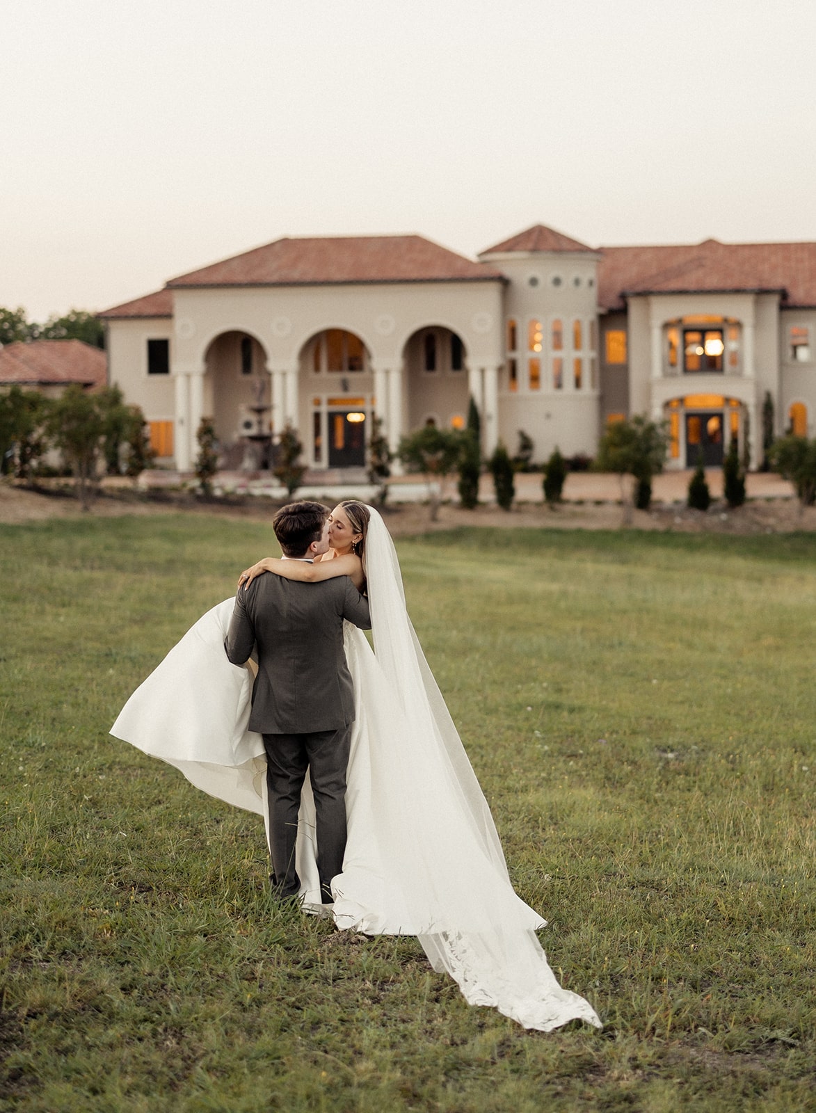 Groom carries bride across the grass at D'vine Grace Vineyard