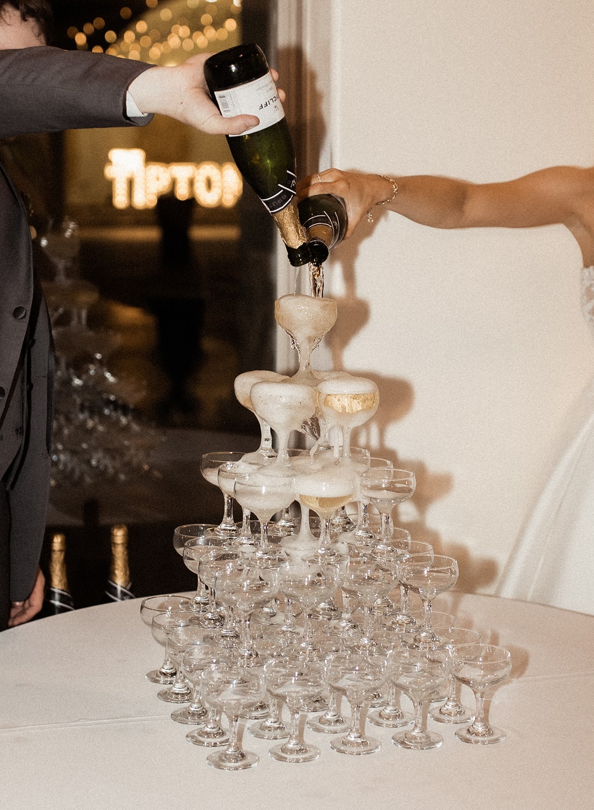 Bride and groom pour champagne into a champagne tower during their wedding reception in Fort Worth, Texas