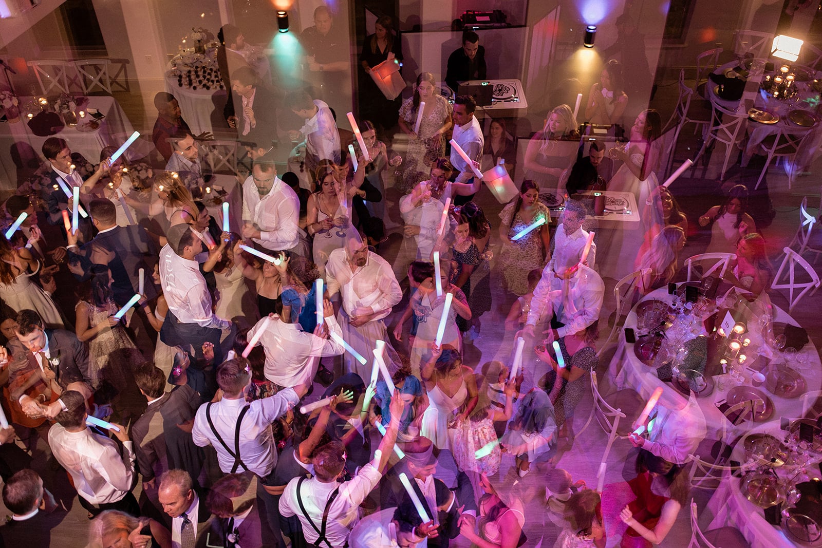 Guests dance on the dance floor with neon light wands