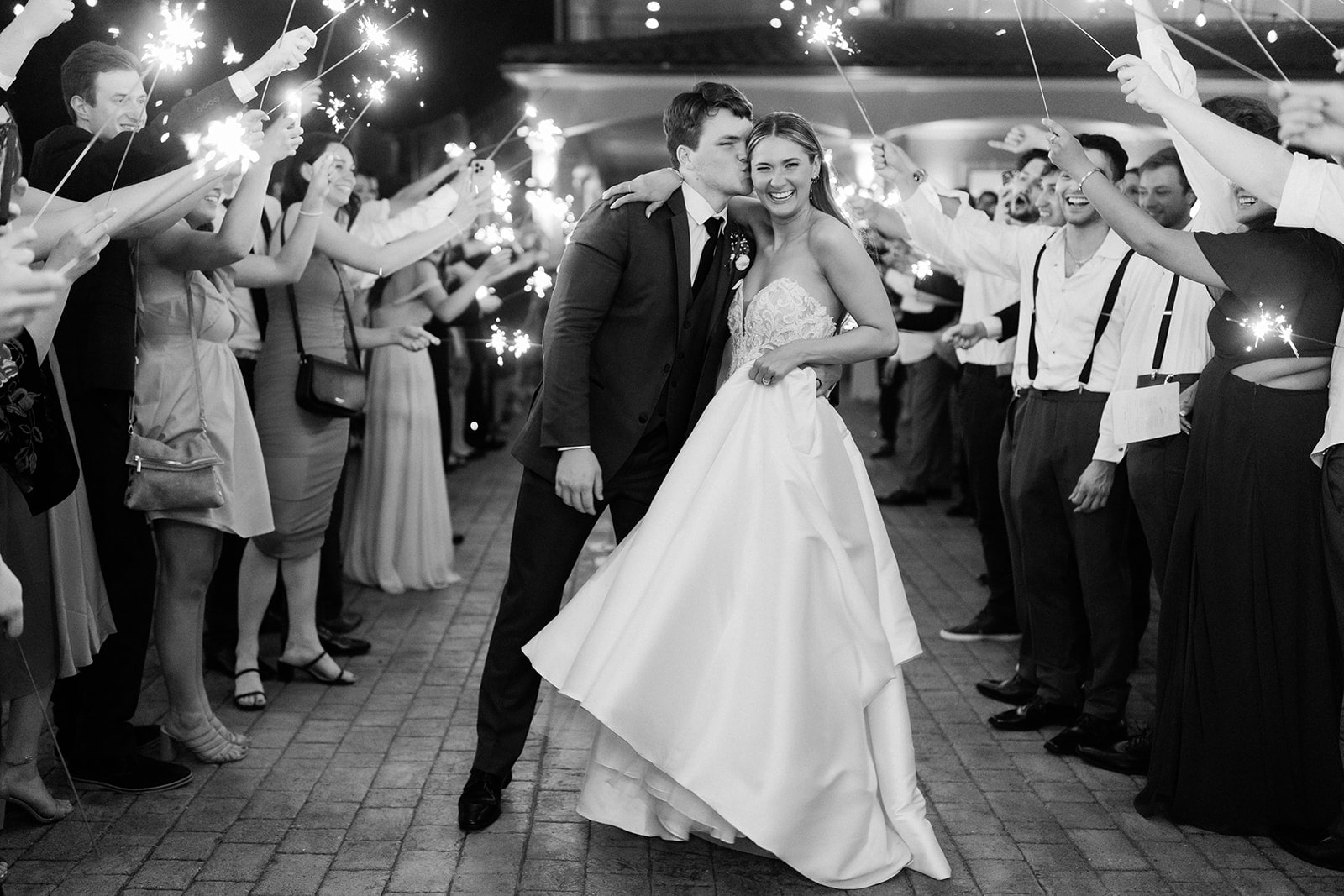 Bride and groom kiss and laugh as they leave their North Texas wedding with a sparkler exit