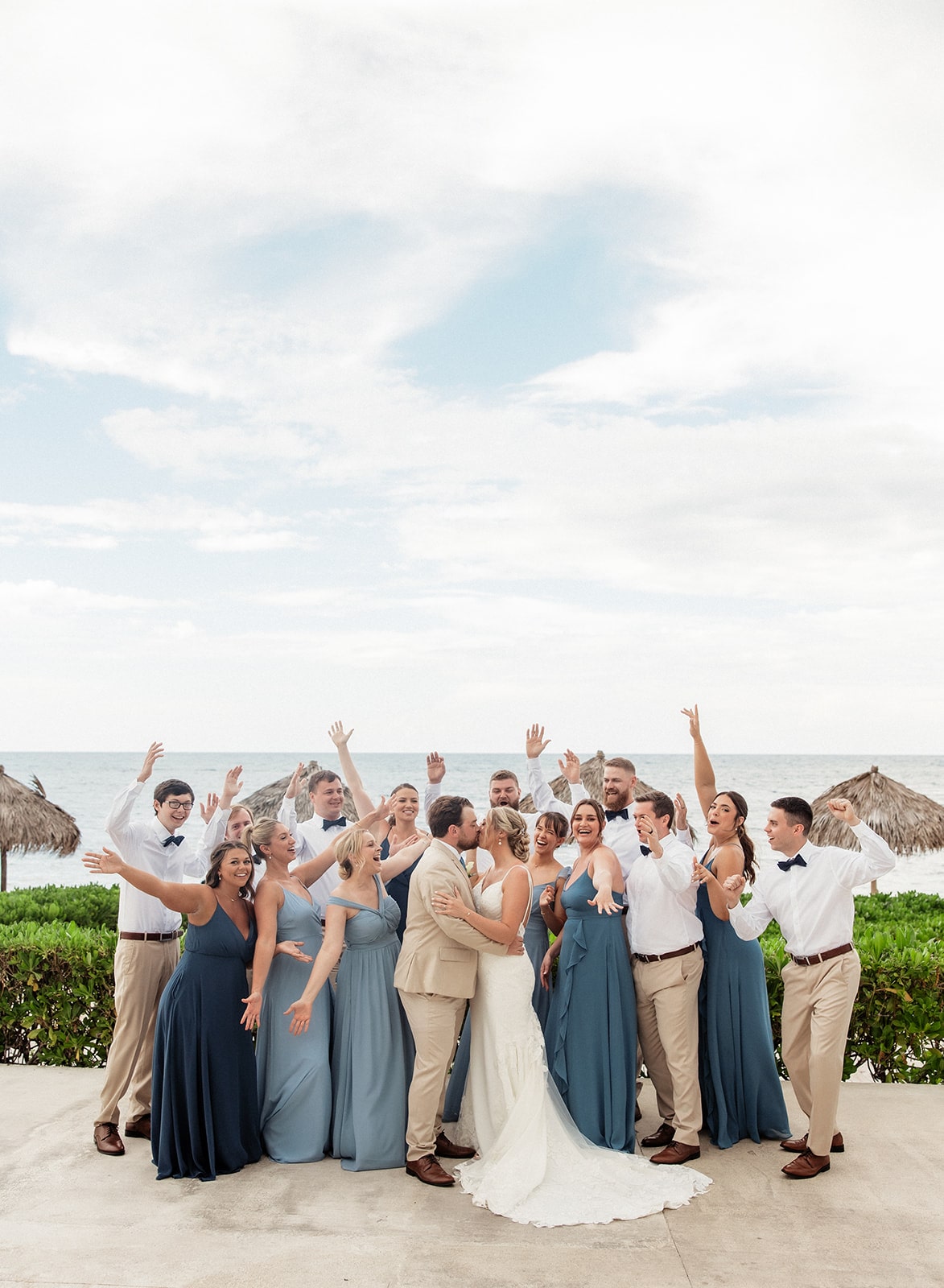 Bride and groom kiss while their wedding party cheers during photos in Jamaica