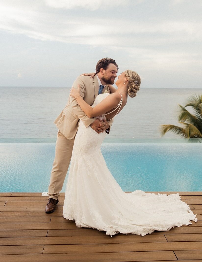 Bride and groom kiss on a pool deck overlooking the ocean at their Montego Bay wedding in Jamaica