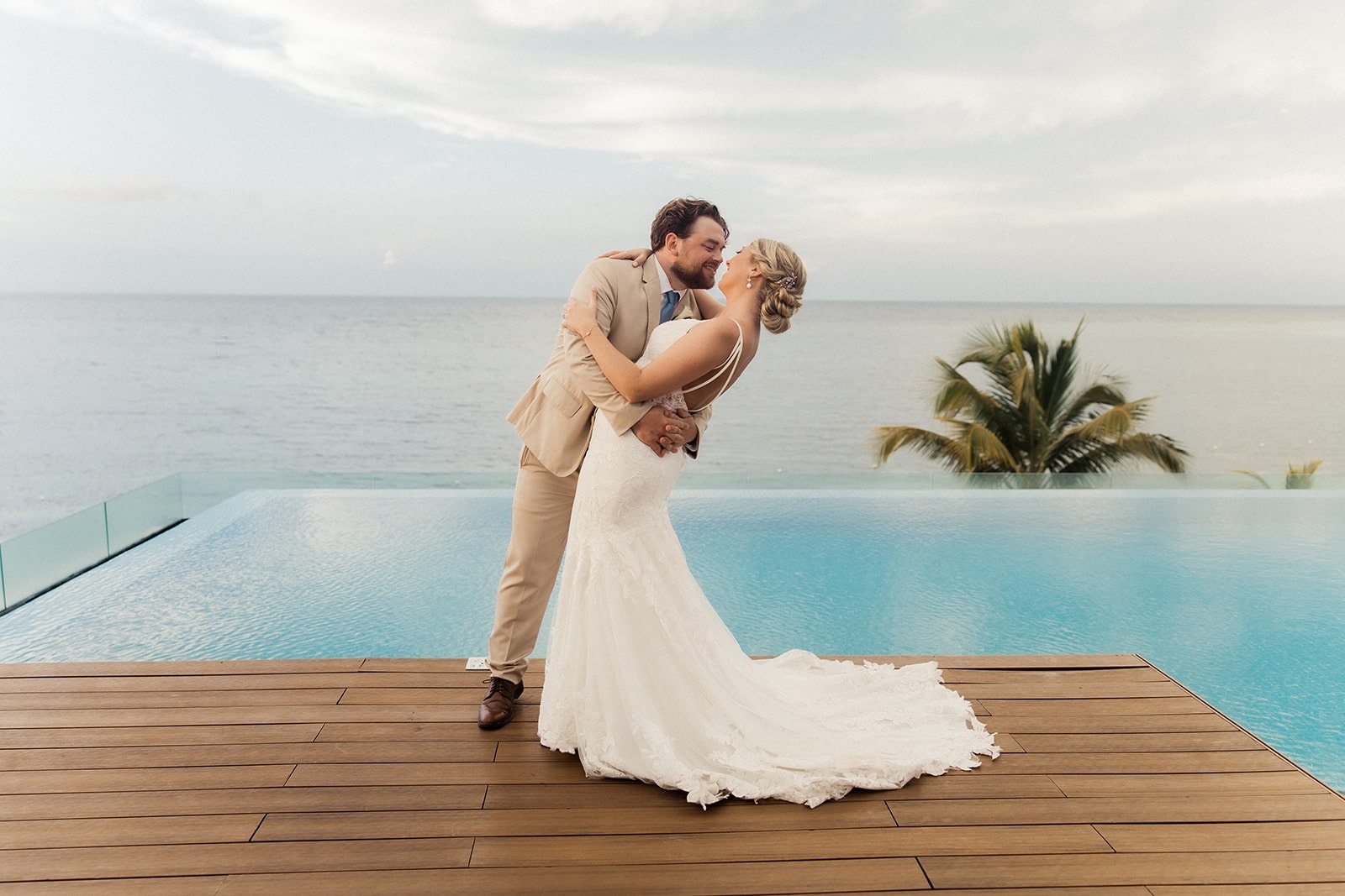 Bride and groom kiss on a pool deck overlooking the ocean at their Montego Bay wedding in Jamaica