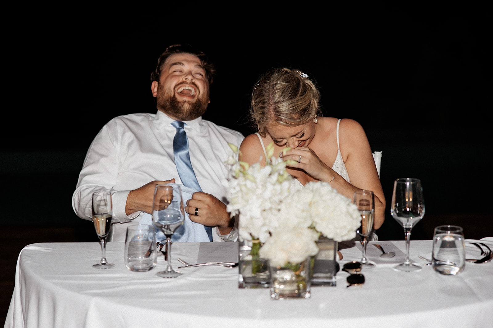 Bride and groom laugh while guests give toasts at their Montego Bay wedding reception in Jamaica