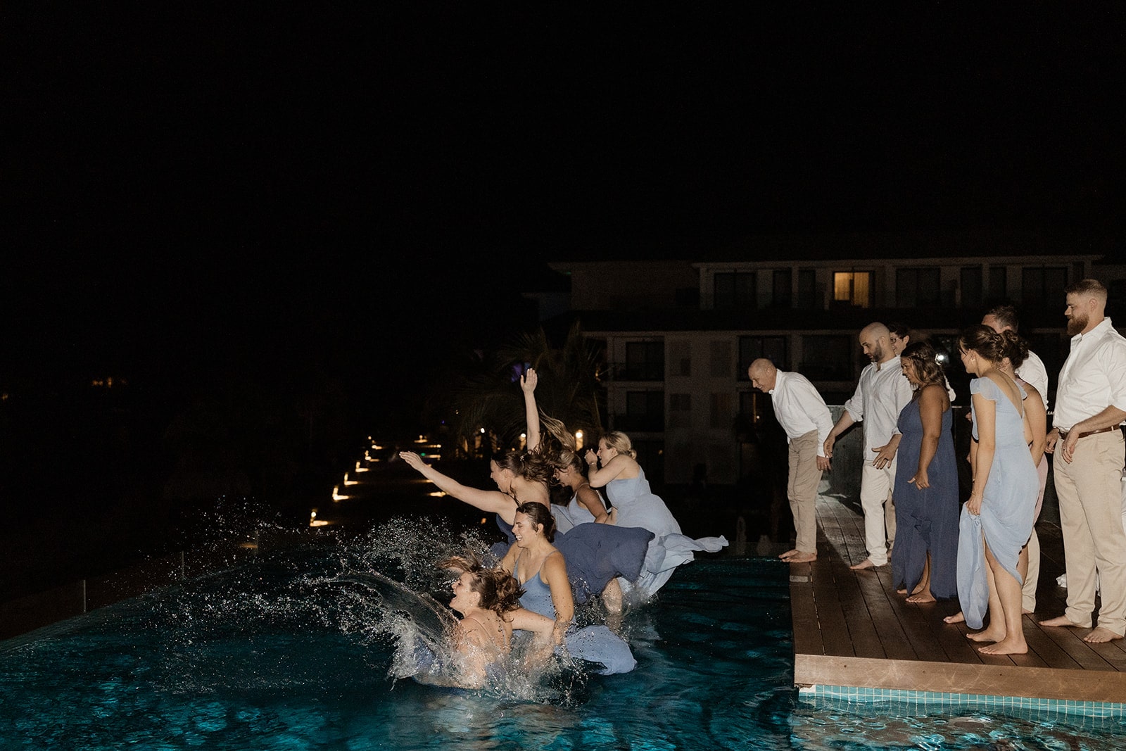 Wedding party jumps into the hotel pool while wearing their blue wedding dresses