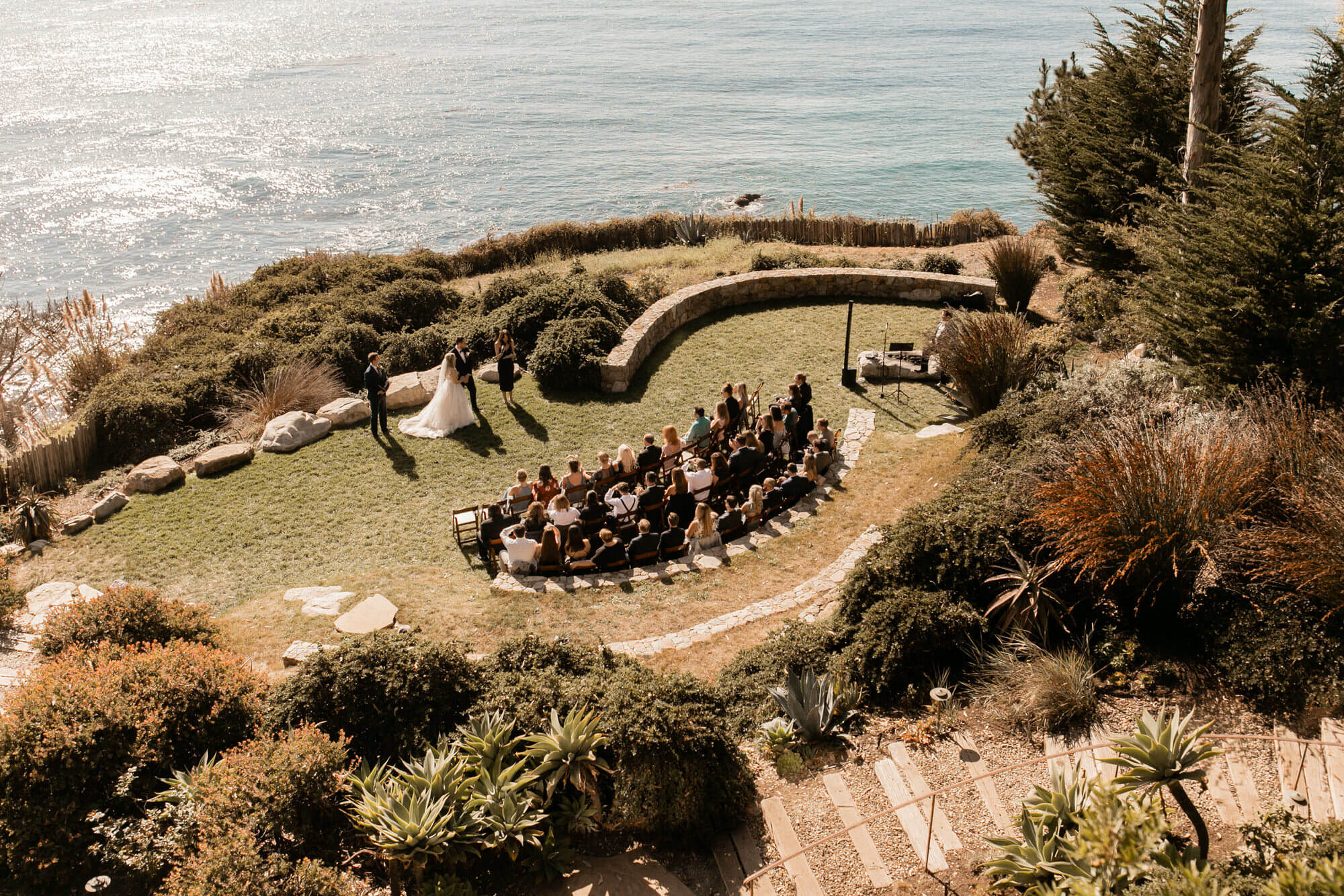 Guests sit on chairs on the lawn during a wedding on the coast of Italy