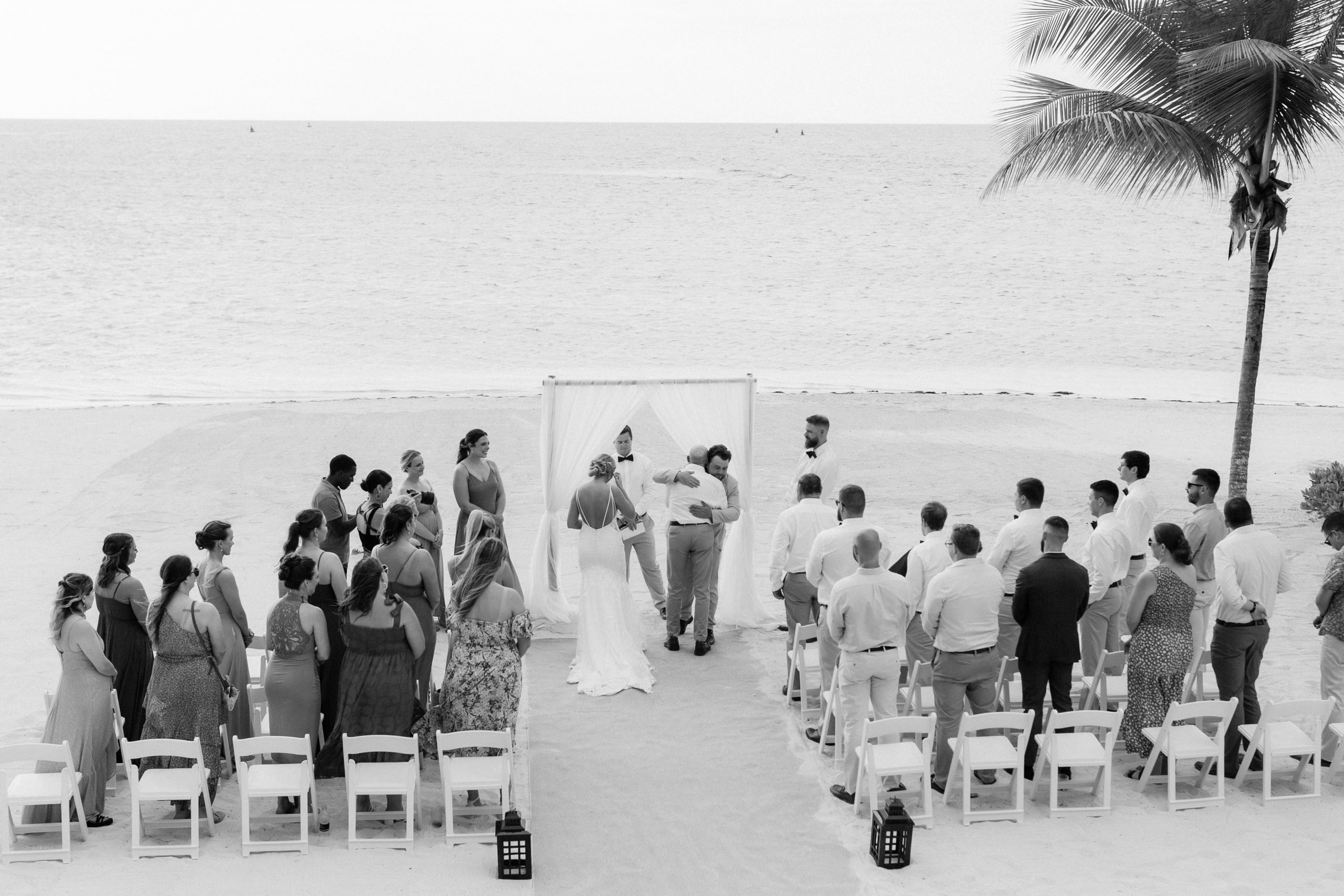 Guests stand and watch bride and groom at the altar during their beach wedding ceremony in Jamaica