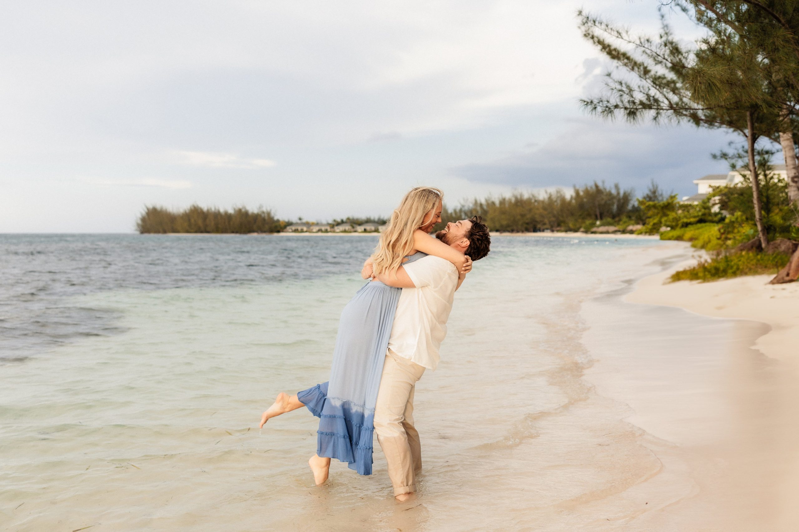 Groom lifts bride up in the air while they kiss on the beach at their Montego Bay resort wedding