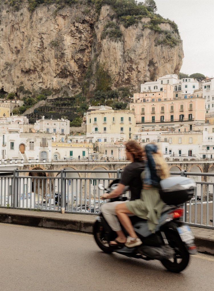 Couple rides a moped through the streets of the Amalfi Coast