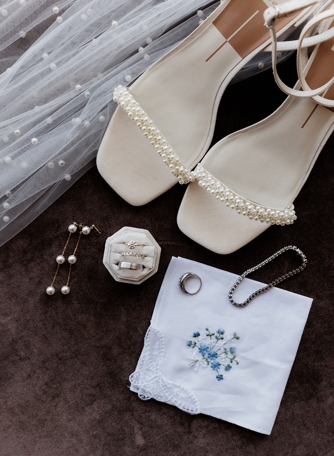 White strappy wedding sandals with pearl and gold earrings and gold and diamond wedding bands with white veil studded with pearls