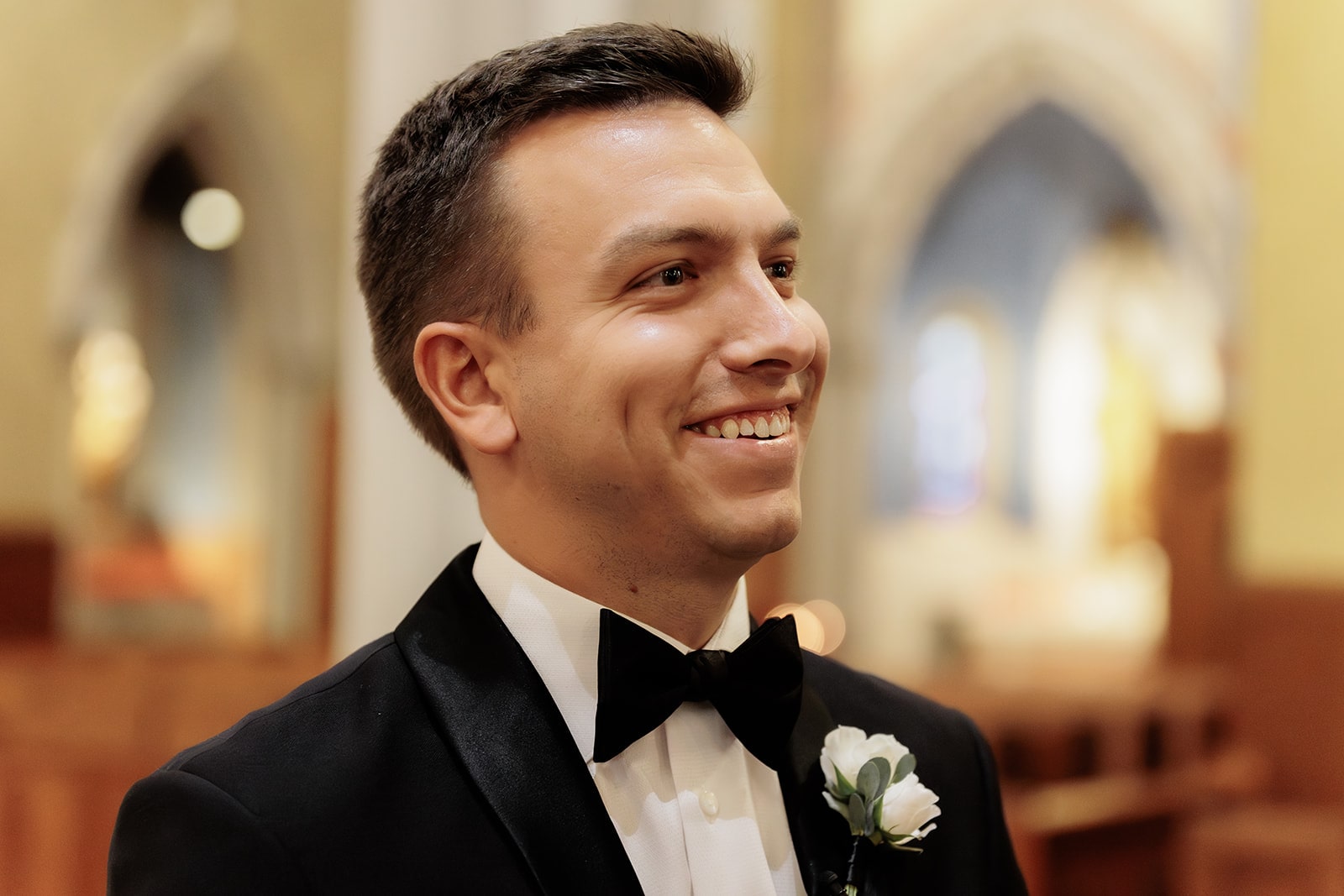 Groom smiles as bride walks down the aisle for their luxury wedding ceremony