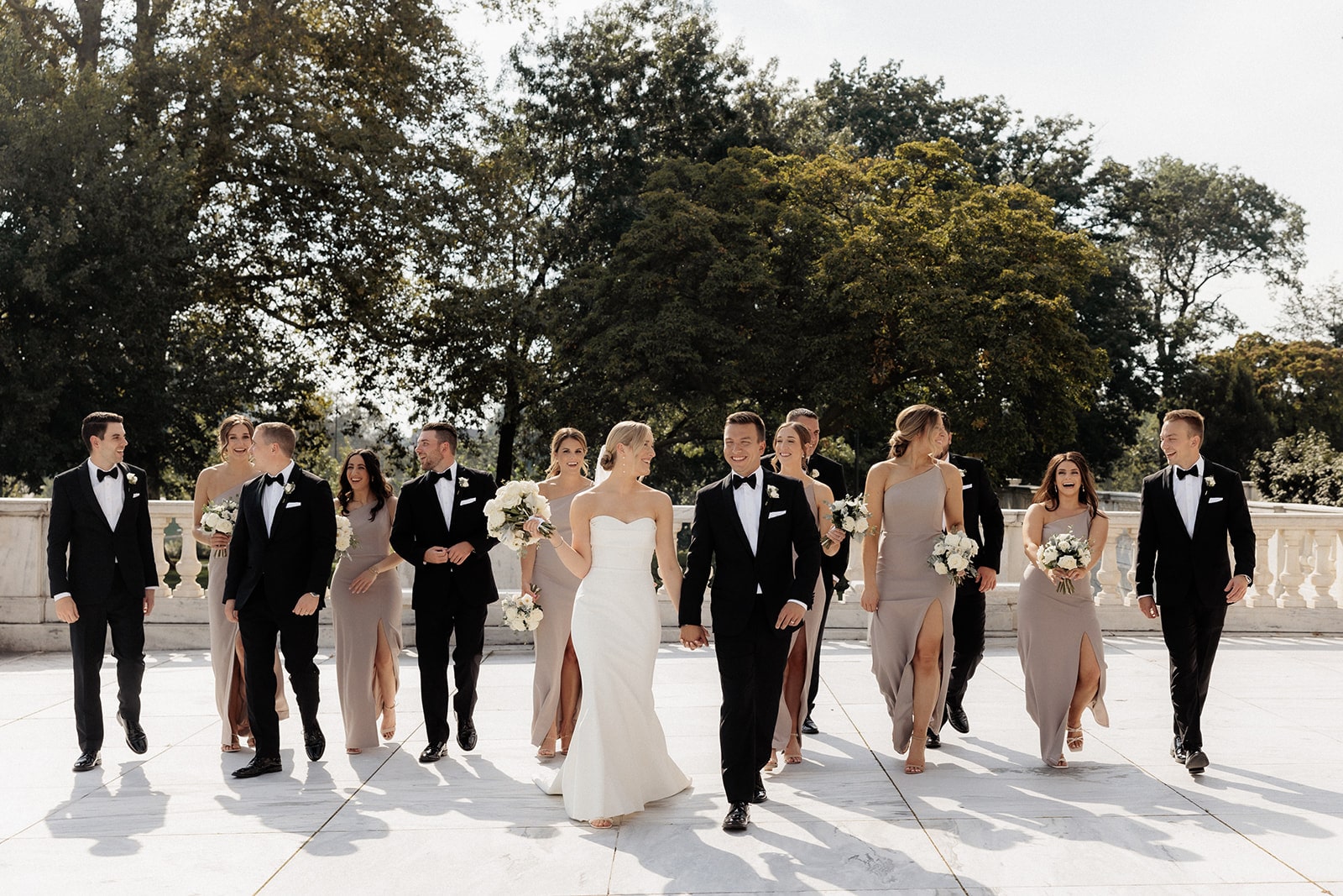 Bride and groom hold hands as they walk with their wedding part at their museum wedding in Ohio