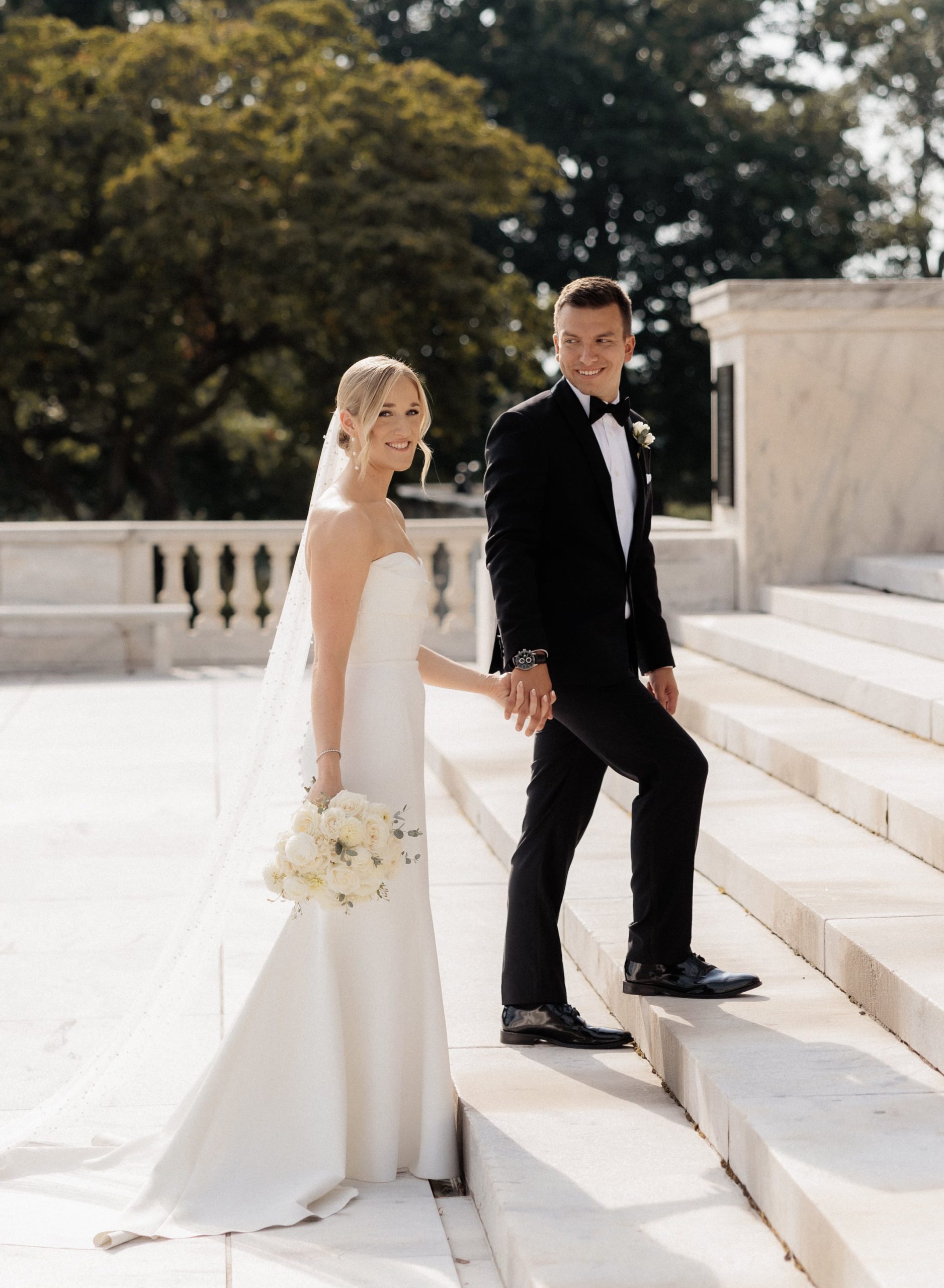 Bride and groom hold hands as they walk up the steps to the Cleveland Museum of Art 