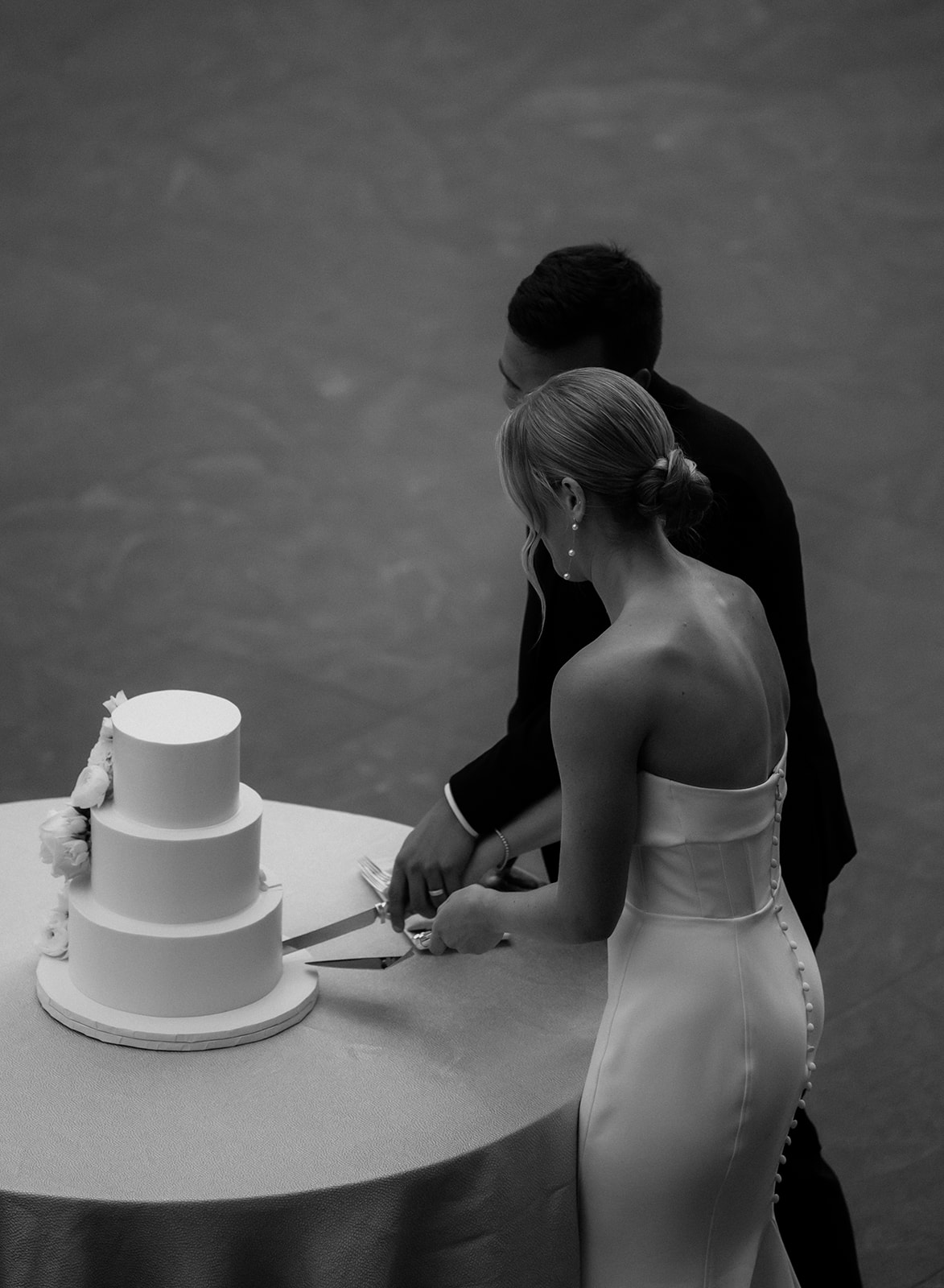 Bride and groom slice their three tier white wedding cake at their museum wedding reception in Cleveland, Ohio